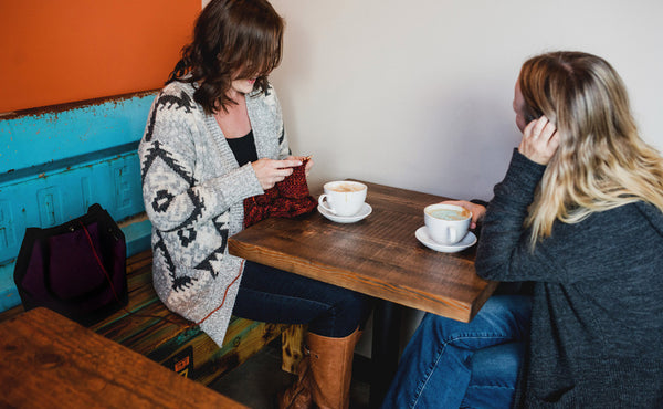 A person knitting out of the Little Swift in a cafe.
